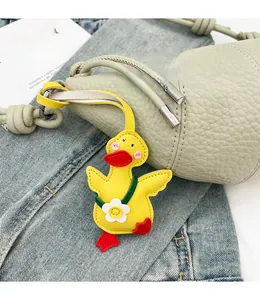 Close-up of a cute yellow duck bag charm on a green textured purse with stitching