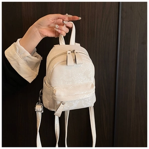 Close-up of white mini backpack with snakeskin pattern texture and metallic zipper detail