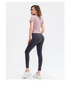 Vista posteriore del top fitness viola slim fit con cuciture e pantaloni da yoga grigi