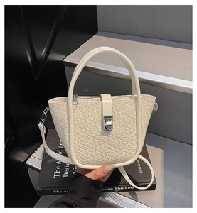 Détail de la texture tressée du sac seau crème avec boucle argentée et poignée