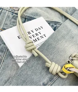Detail of adjustable knotted shoulder strap on sage green textured leather dumpling bag