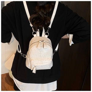 Close-up of white mini backpack with snakeskin texture and silver ring details