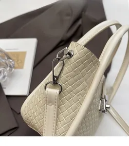 Détail du sac seau en cuir tressé crème avec ferrures argentées et fine bandoulière cuir