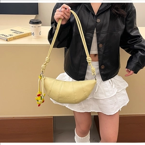 Detail of light yellow crescent bag featuring lychee grain leather and knotted strap