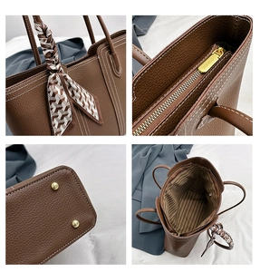 Detail view of brown pebbled leather tote with contrast stitching and metal zipper closure