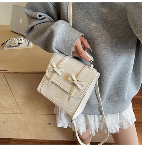 Detailed view of cream bow shoulder bag with lychee texture leather and logo