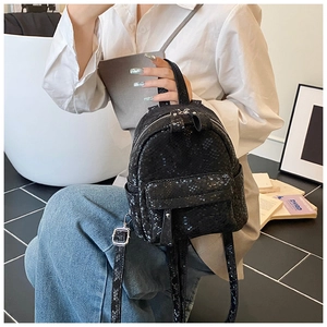 Detail of a mini black backpack with snakeskin texture and silver zippers on a side pouch