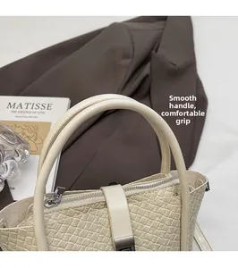 Détail d'un sac seau tressé crème avec poignée arrondie et texture de qualité