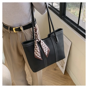 Close-up of black faux leather tote bag with lychee texture and white stitching details