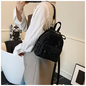 Detail showing snake-patterned black mini backpack with bow zipper and adjustable straps