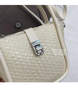 Gros plan du sac tressé crème montrant la texture et le fermoir métallique pivotant