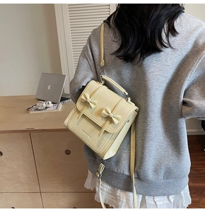 Detail of creamy yellow PU leather crossbody bag featuring two stylish 3D bow accents