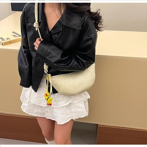 Detail of beige crescent bag with rope knot strap and cute yellow duck charm