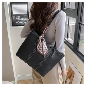 Close-up of black pebble leather tote bag with white contrast stitching and a stylish scarf