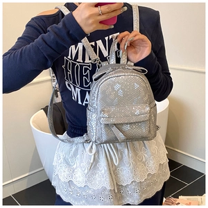 Mirror selfie showing a mini silver backpack with textured snakeskin finish and slim straps