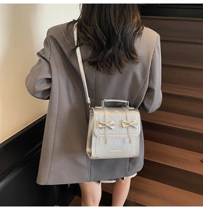 Detail of silver pleated texture shoulder bag with bow accents worn by a model