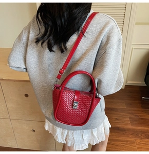 Detail shot of the red woven pattern texture and silver swivel lock on a stylish bucket bag