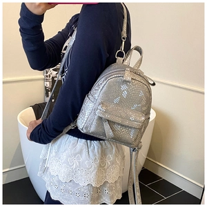 Detail of silver faux snake pattern texture and zip pockets on mini backpack