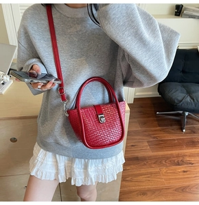 Close-up of red woven texture and elegant silver metal buckle on a bucket handbag