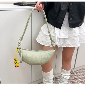 Detail of light green croissant bag with lychee texture and cute duck charm