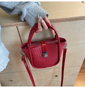 Detail of red woven texture on a trapezoid handbag with metal buckle and shoulder strap