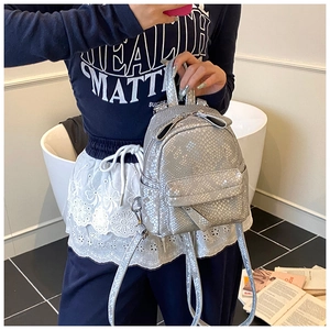Detail of a mini silver faux leather backpack with metallic snakeskin texture and zippers