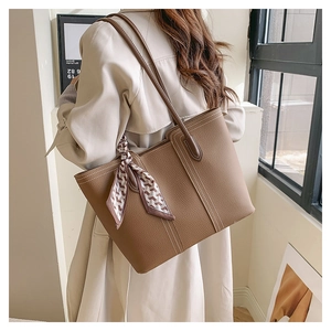 Close-up of brown litchi texture tote bag with white stitching and silk scarf detail