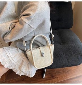 Détail du sac à bandoulière tressé crème avec fermoir rotatif argenté et anse ronde