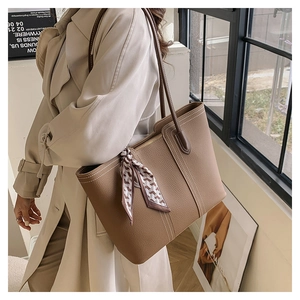 Detail of tan pebble leather tote bag with white contrast stitching and silk scarf