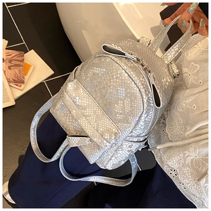 Detail of silver snake-patterned mini backpack with metallic finish and front zipper pocket