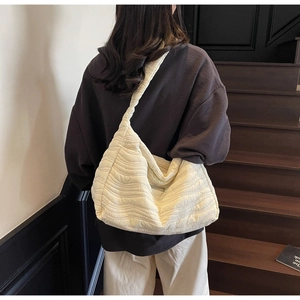 Detail of a creamy white quilted tote bag with soft bubble texture shown on a model