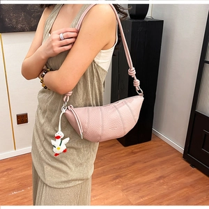 Close-up of pink crescent handbag with lychee texture leather and a cute duck pendant