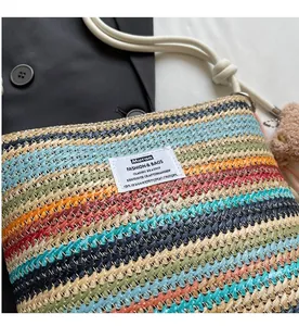 Detail of colorful woven stripe bucket bag with white cord handle and plush charm decor