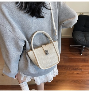Model wearing an off-white woven texture bucket bag with silver metal rotating lock