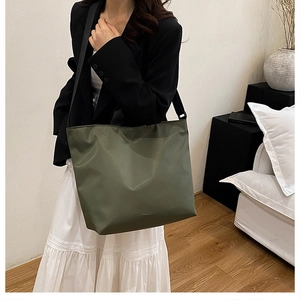 Lifestyle view of large olive green tote bag with wide black strap for commuters