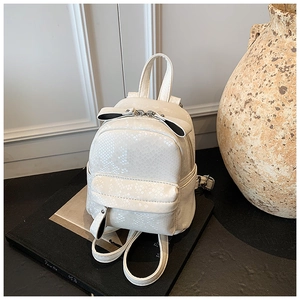 Detail of white faux leather backpack with snake pattern and decorative bow zipper