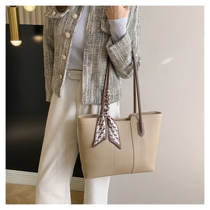 Detail of apricot faux leather tote bag featuring a decorative geometric silk scarf handle