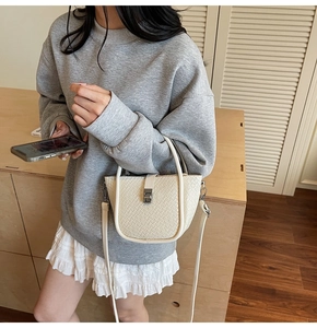 Detail showing the cream woven texture and silver metal buckle of the bucket bag