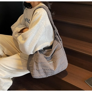 Detail of the wave quilted shoulder bag with metal accent on a brown wooden staircase