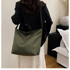 Rear view of model wearing a large olive green nylon tote bag with black shoulder straps