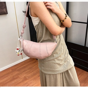 Detail of light pink lychee pattern crescent bag with knotted strap and cute duck pendant