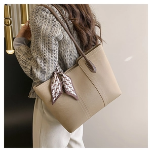 Detail of khaki lychee leather tote bag with elegant silk scarf on shoulder strap