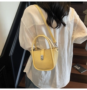 Détail du sac seau tissé jaune avec fermoir métallique argenté et double poignée
