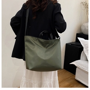 Rear view of model wearing military green nylon tote bag with black adjustable strap