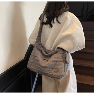 Detail view of large quilted taupe shoulder bag showing wave stitch texture and strap