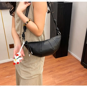 Close-up of black croissant bag with lychee grain leather texture and knot strap detail