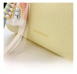 Close-up of yellow pebbled leather handbag with gold logo and colorful decorative charms