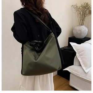 Large olive green tote bag showing spacious capacity and wide black shoulder strap on model