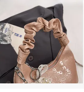 Detail of pink glossy leather handbag featuring cloud ruched handle and elegant pearl charm