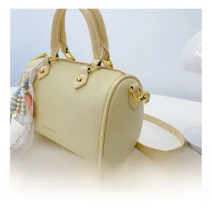 Detailed close-up of beige leather boston bag with golden hardware and fringe charm